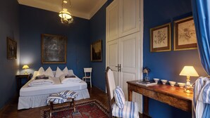 Ein Schlafzimmer mit einem Bett, Nachttischen, einem Sessel, einem Schreibtisch und einem Kleiderschrank.