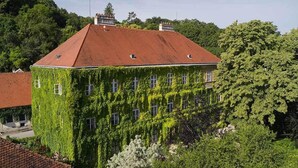 A building with a red roof and ivy-covered walls, surrounded by trees.