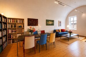 A modern living room with a dining area, bookshelves, and artwork.
