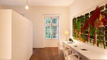 A modern room with a white desk, chairs, a lamp, and a large abstract painting on the wall.