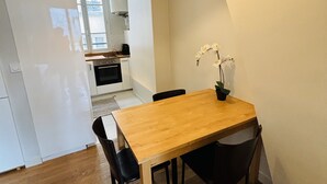 Een eetgedeelte met een houten tafel en zwarte stoelen, een kleine potplant en een lamp erboven.