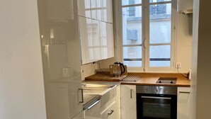 Een keuken met witte kastjes, een houten aanrecht, een waterkoker en een oven.