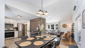 A modern kitchen with a dining area, featuring a large island, built-in appliances, and a contemporary chandelier.
