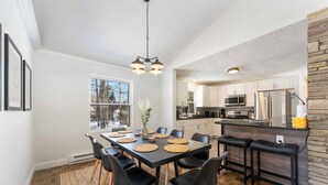 A modern kitchen with white cabinets, a central island, and a dining area with a large table and chairs.