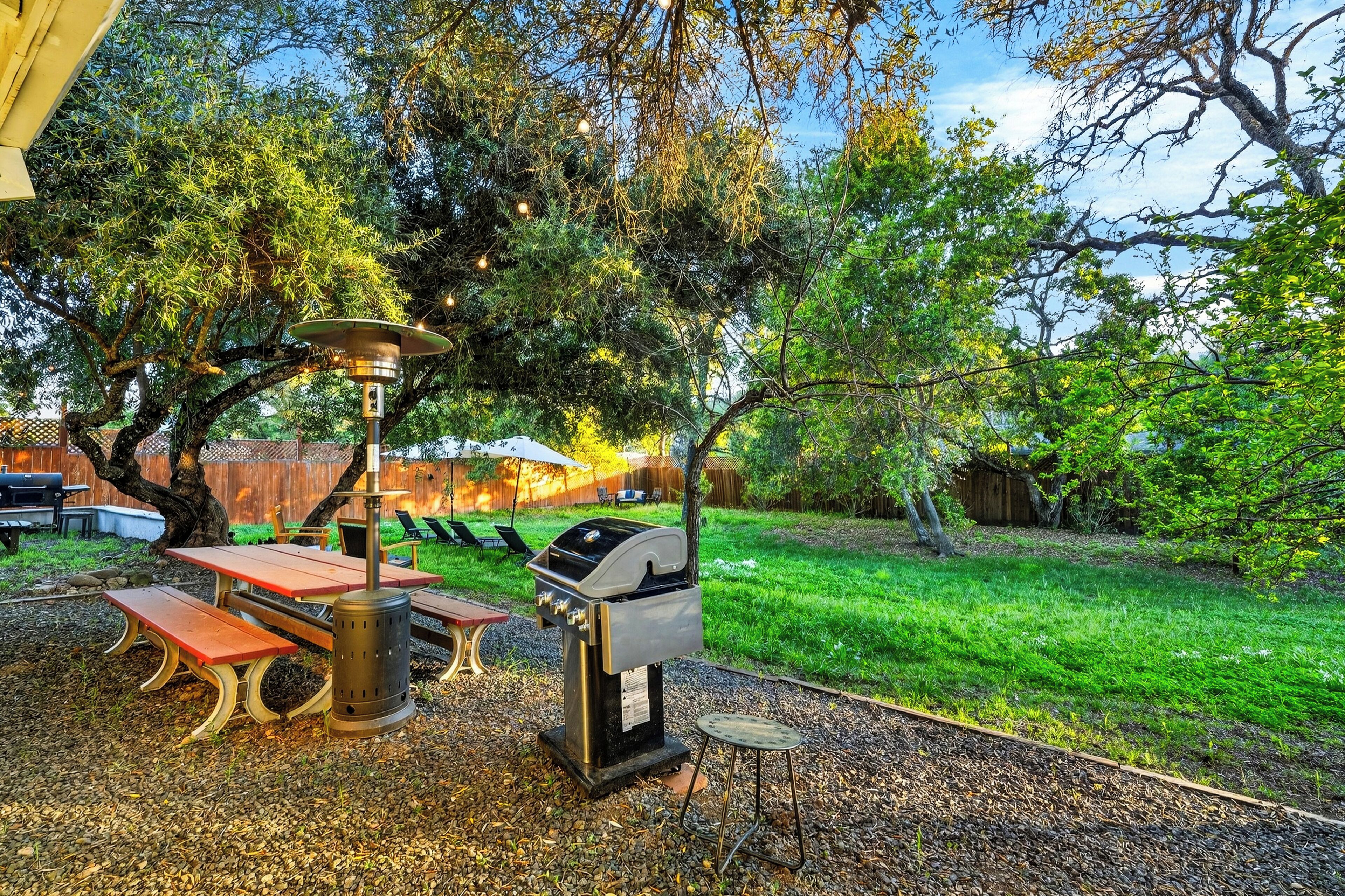 Un patio al aire libre con una parrilla, una mesa de picnic y bancos.