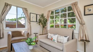 A cozy living room with a beige sofa, a coffee table, and a potted plant. - Hobby Vineyard + Firepit + Outdoor Living + EV Charger | Grapevine Cottage (Glen Ellen)