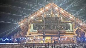 Un grand bâtiment en bois, illuminé, doté d’un espace central avec des sièges et d’un balcon.