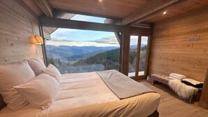 Une chambre avec un grand lit, un banc et une vue sur les montagnes.