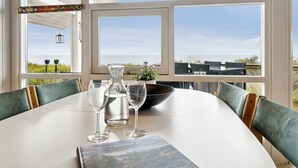 Ein Essbereich mit Tisch für zwei Personen, große Fenster mit Meerblick und einer darüber hängenden Laterne.