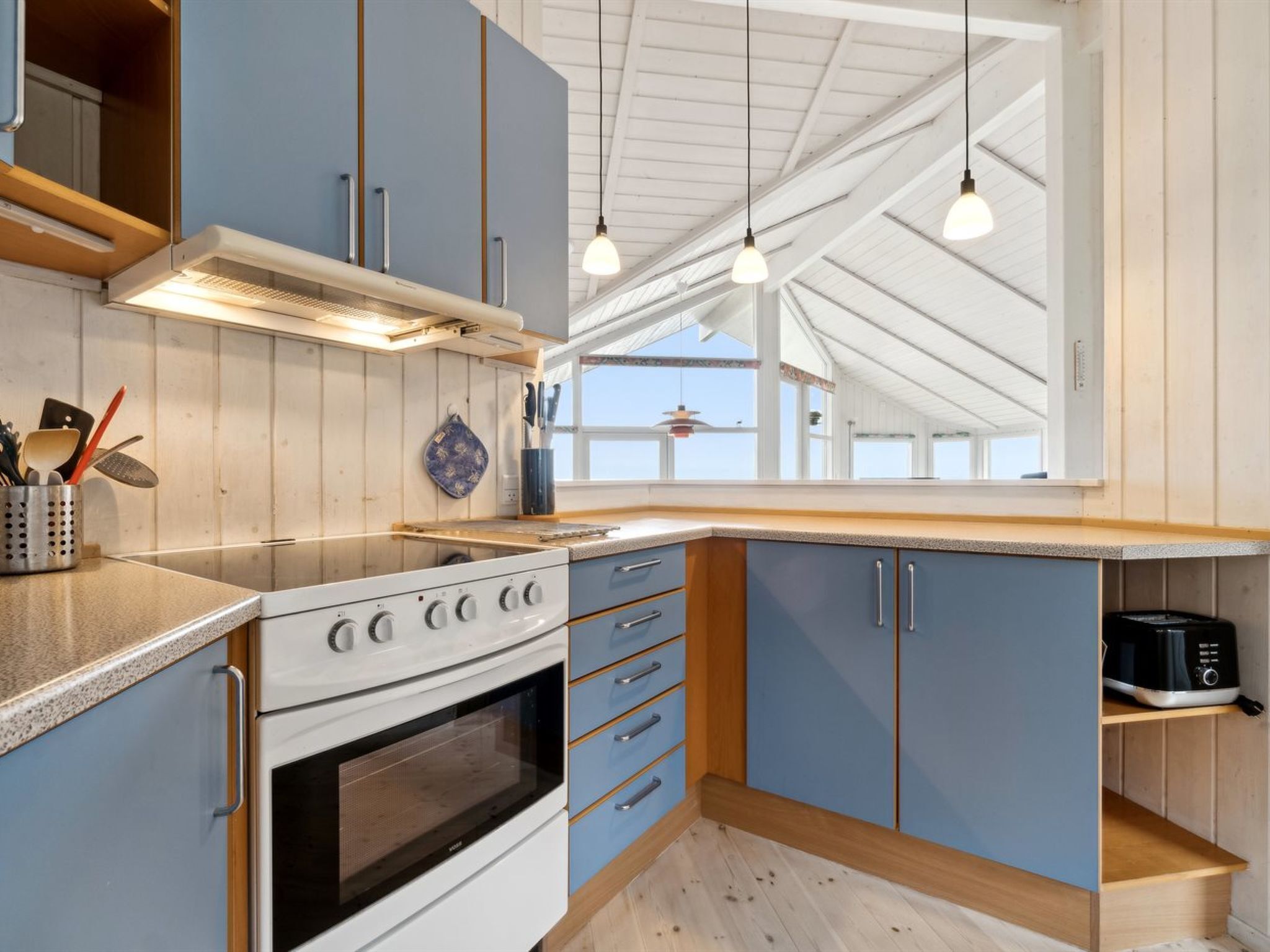 A modern kitchen with a large window, wooden cabinets, and a built-in oven.