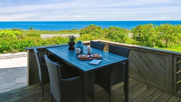 Eine Terrasse mit Tisch für zwei Personen, mit Blick auf die Küste.