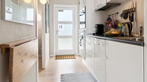 Una cucina moderna con mobili bianchi, un piano di lavoro nero e un forno a microonde sopra il lavello.