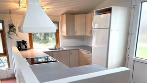 Eine moderne Küche mit weißen Schränken, einem eingebauten Herd und einem großen Fenster für natürliches Licht.