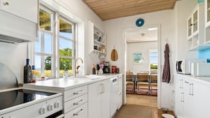 Eine moderne Küche mit weißen Schränken, einem eingebauten Backofen und einem großen Fenster.