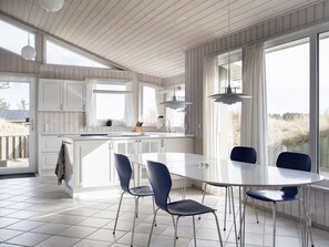 Una cucina moderna con mobili bianchi, un'isola centrale e un'area pranzo con un tavolo rotondo e sedie blu.