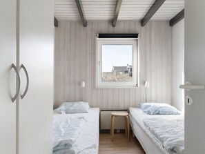 Camera da letto con due letti, una finestra e un soffitto in legno.