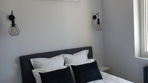 Een moderne slaapkamer met een bed, witte muren, een plafondventilator en een raam.