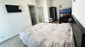 A bedroom with a bed, a TV mounted on the wall, a wardrobe, and a bunk bed. - Strategic in the green between Terracina Sabaudia and Circeo (Lazio)