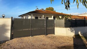 A gated property with a white building, a gravel driveway, and a clear blue sky. - Strategic in the green between Terracina Sabaudia and Circeo (Lazio)