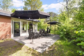 Relax under the shade of a large umbrella, surrounded by lush greenery and a tranquil atmosphere.