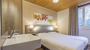 A hotel room with a wooden ceiling, a large bed with white bedding, a white sink, and two bedside lamps. - Relax & Unwind in Putten (Putten)