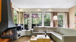 A modern living room with a fireplace, a sofa, a coffee table, and large windows with curtains. - Relax & Unwind in Putten (Putten)