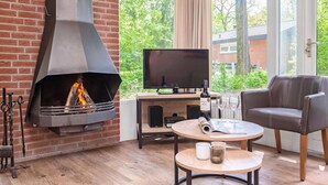 Un salon chaleureux avec une cheminée, un téléviseur et un coin salon confortable.