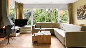 En moderne stue med et stort vindue, et fladskærms-tv, et træ sofabord og en beige sofa.