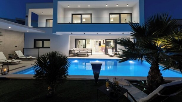 A modern two-story house with a swimming pool, lounge chairs, and a well-lit interior. - Villa Golden Shine with heated pool, Primošten (Primošten)