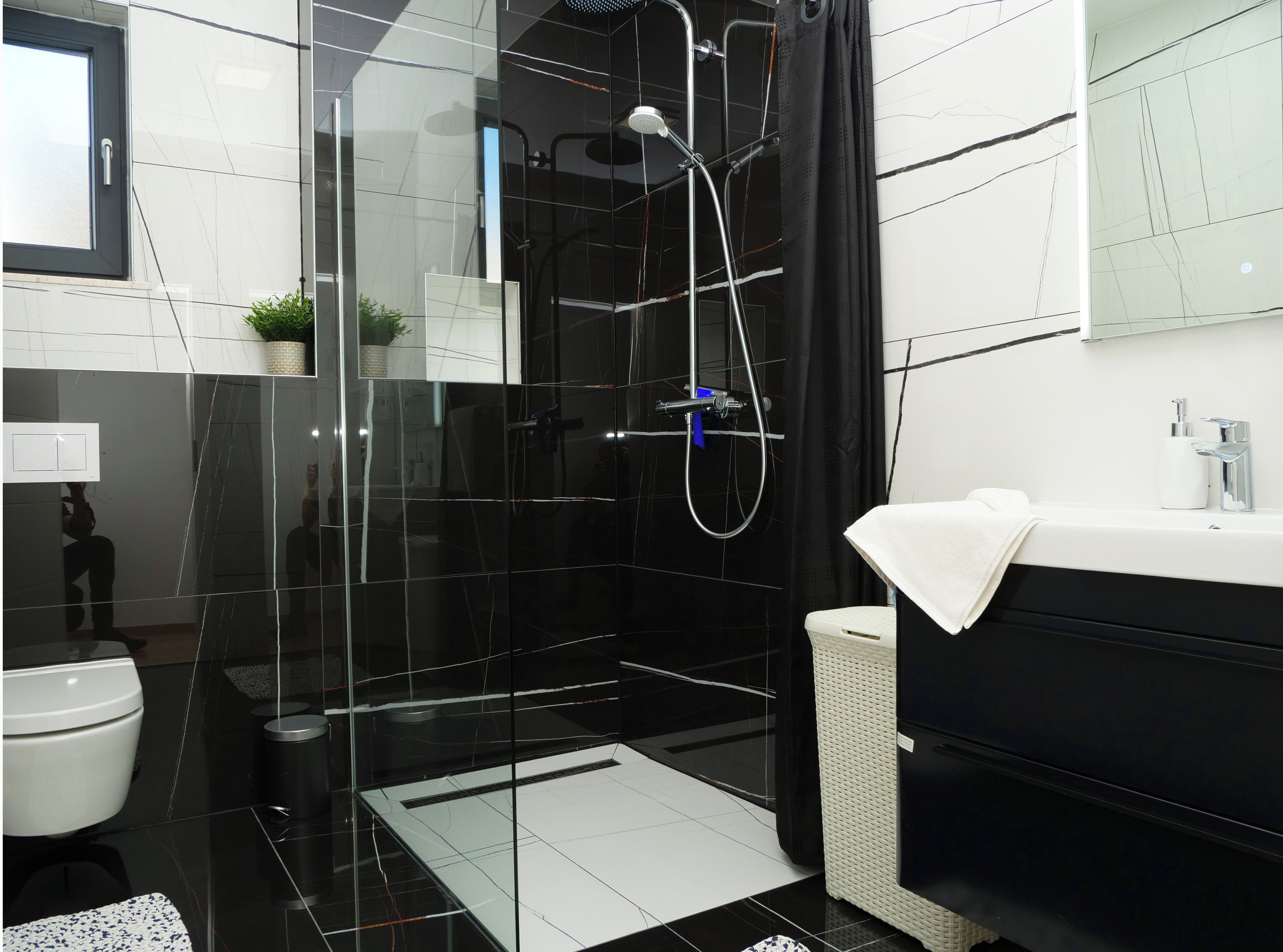 A modern bathroom with a glass-enclosed shower, a white sink, and a black vanity.