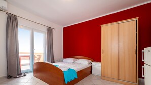 A bedroom with a bed, a wardrobe, a nightstand, and a sliding door to a balcony. - Bonvie Apartments in Center 12 B6 (Novalja)