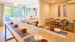 A dining area with a long wooden table set for a meal, surrounded by chairs.
