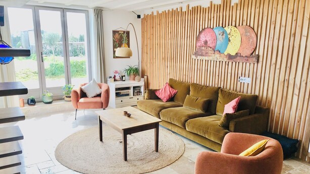 A modern living room with a sofa, armchair, coffee table, and a wooden wall panel.