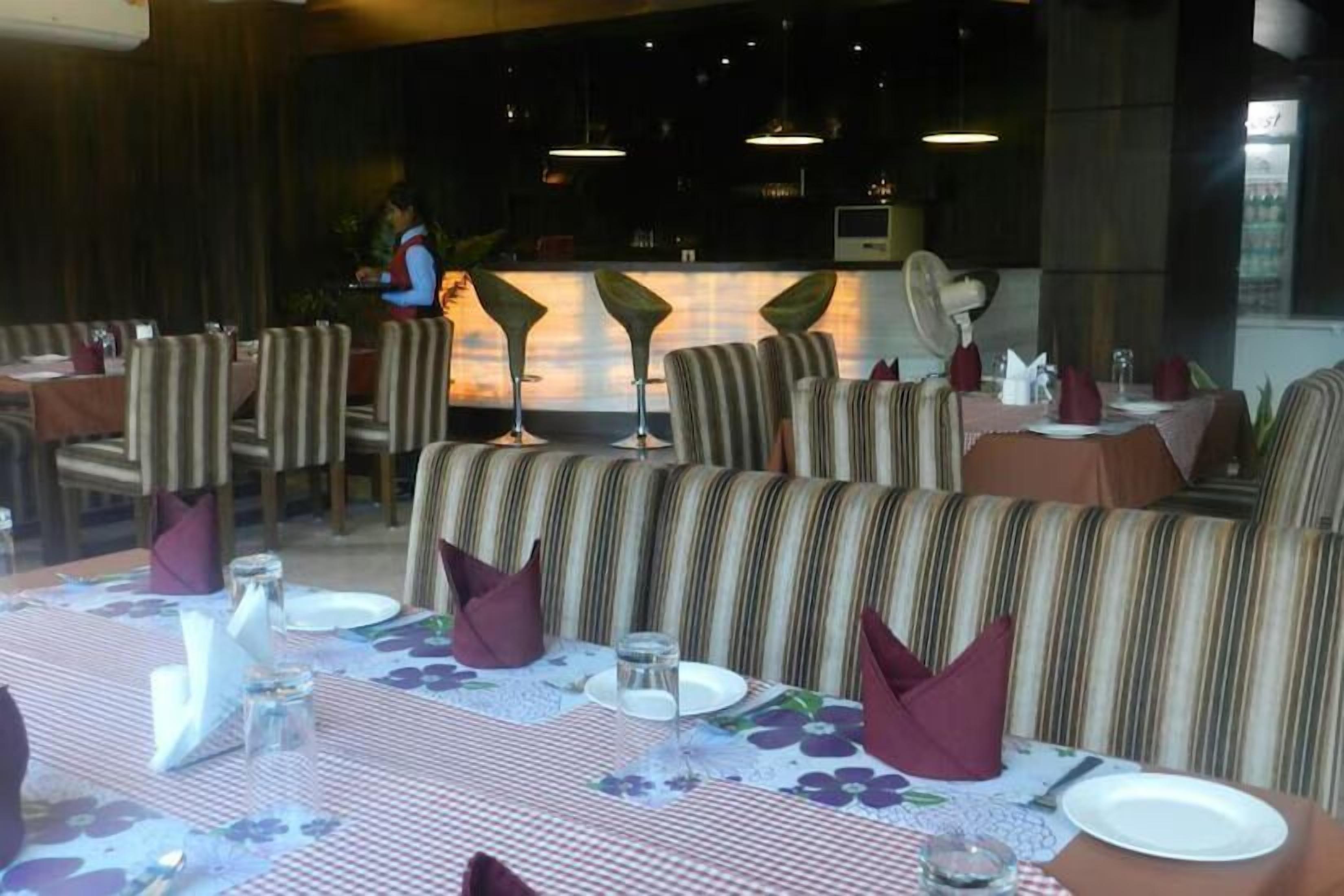 A restaurant with striped booths and tables set with white plates, napkins, and glasses.