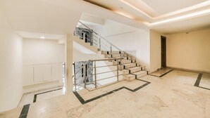 Un ambiente spazioso con pavimento in marmo, una scala con ringhiere in metallo e un design moderno.