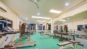 Una palestra con tapis roulant, panche pesi e diverse attrezzature per allenamento.