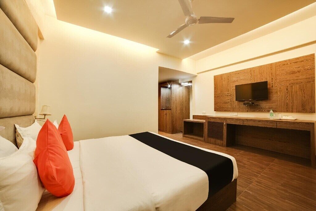 Ein modernes Hotelzimmer mit einem großen Bett, einem Holztisch, einem Flachbildfernseher und einem Deckenventilator.