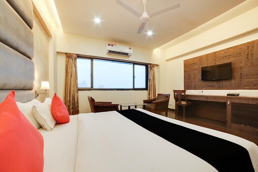 A hotel room with a bed, a desk, a chair, a television, and a window with curtains.