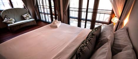 Een hotelkamer met een groot bed, een bank met kussens en een raam met gordijnen.