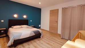 Ein Schlafzimmer mit einem Bett, Nachttischen, einem Kleiderschrank und einem Vorhang.