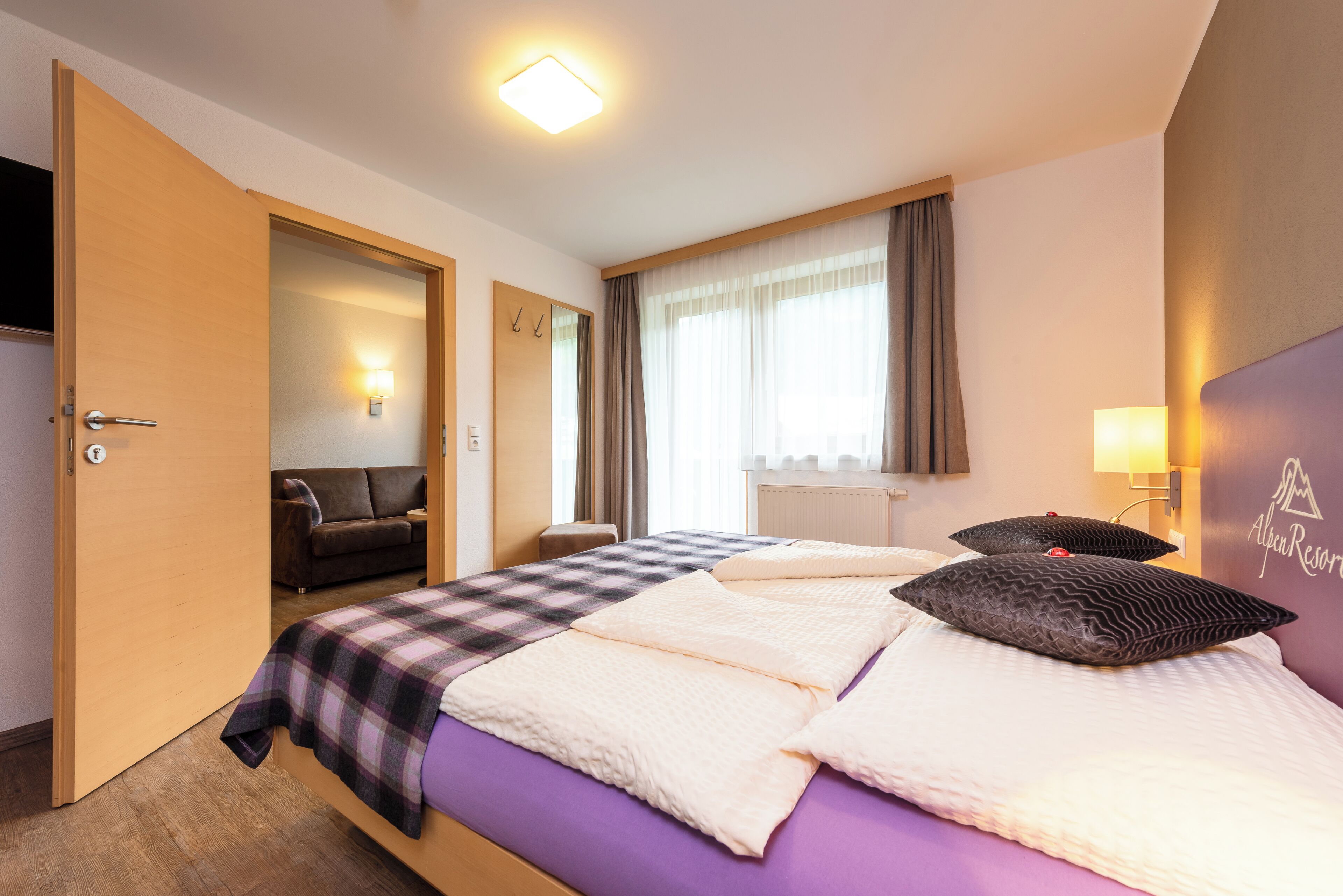 Ein Hotelzimmer mit Bett, Sofa, Schreibtisch und einem Fenster mit Vorhängen.
