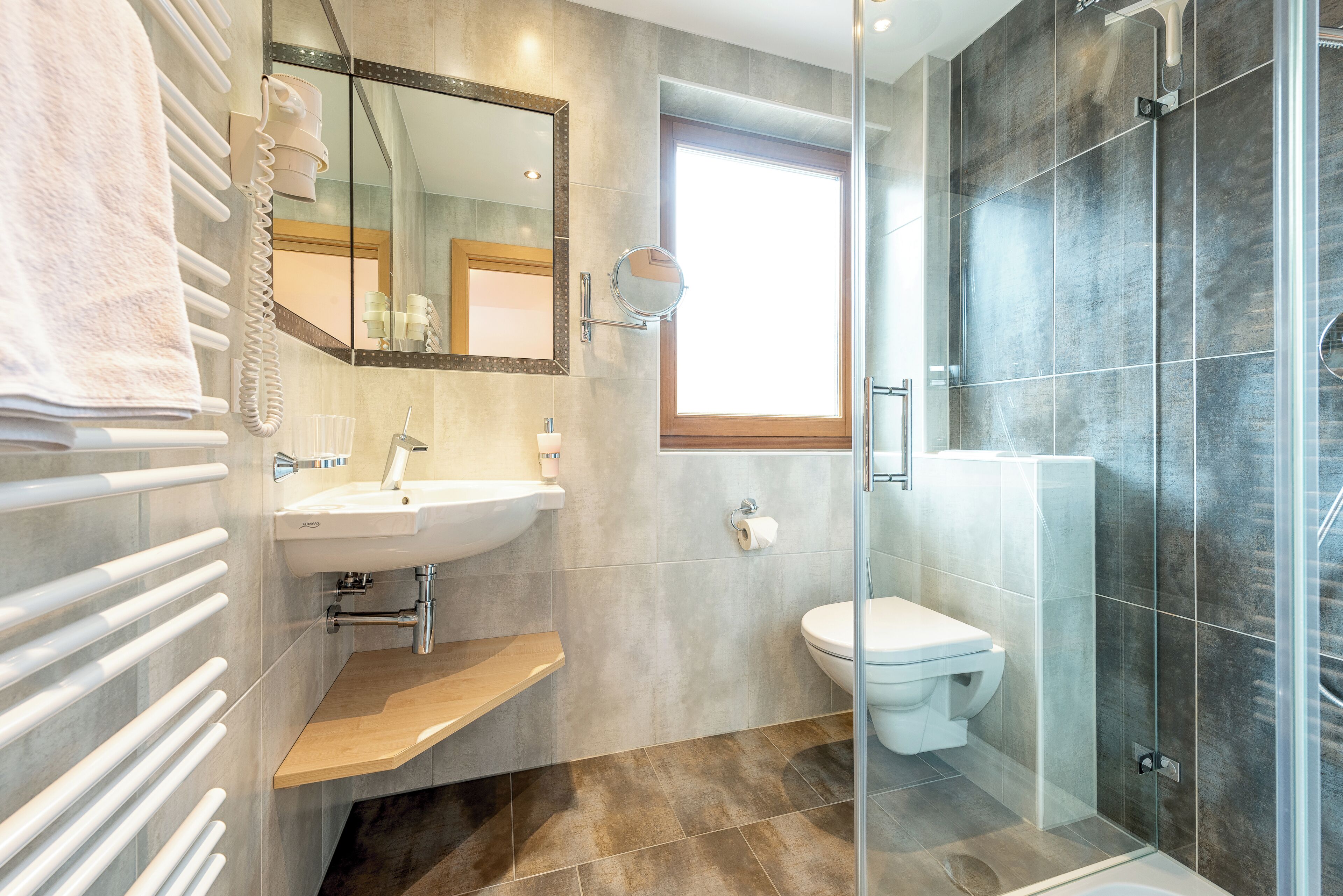 A modern bathroom with a glass shower enclosure, a white sink, and a toilet.