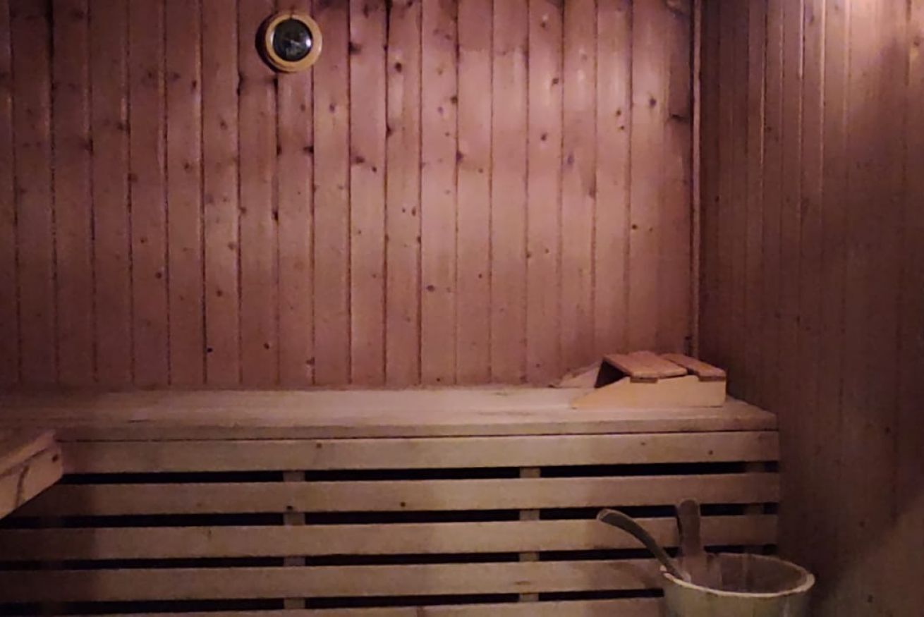 A wooden sauna with benches and a bucket.