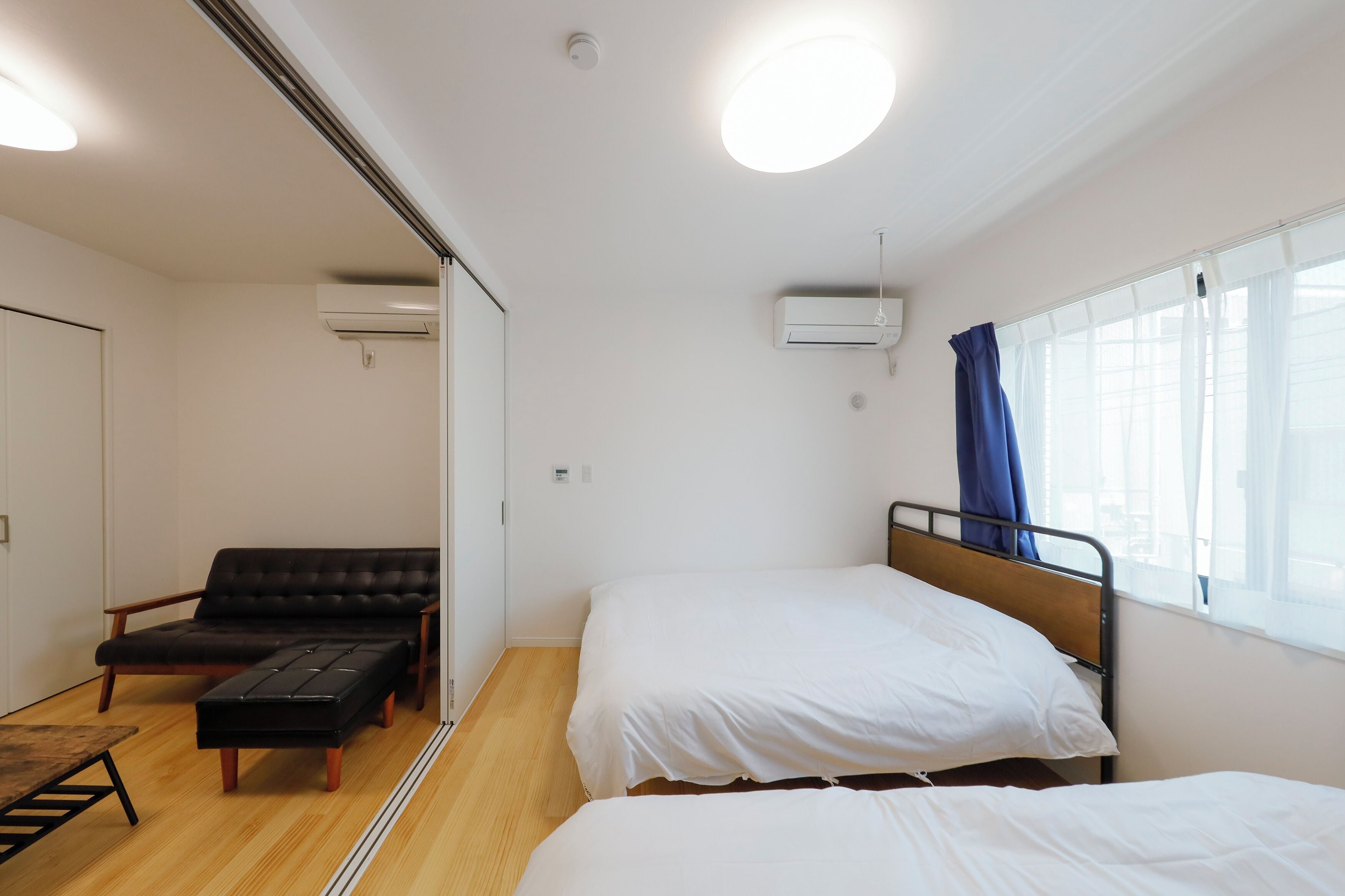 A small, clean room with a bed, a sofa, and a table.