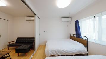 A small, clean room with a bed, a sofa, and a table.