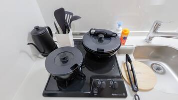 Een keuken met een fornuis, waterkoker en spoelbak.