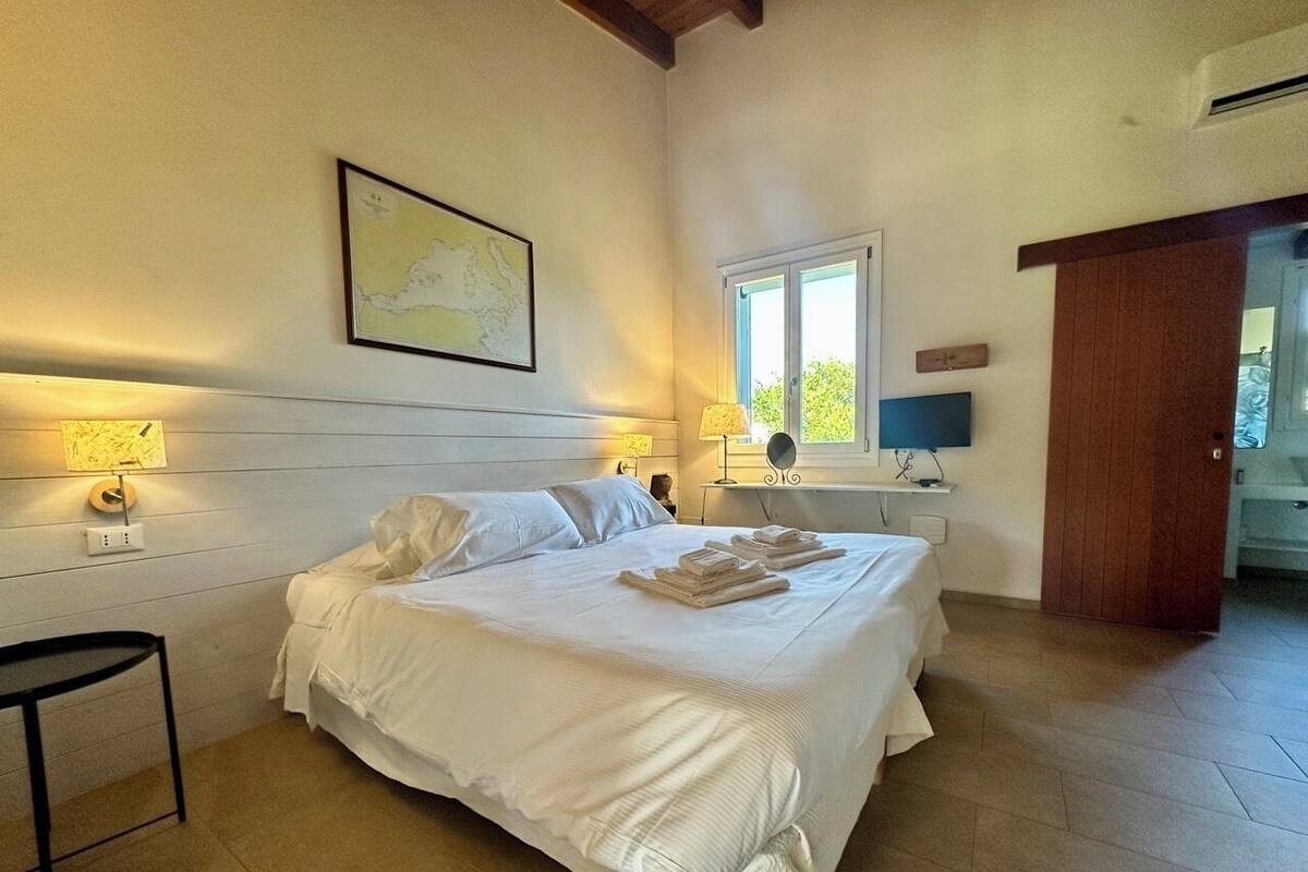 Une chambre avec un grand lit, des tables de chevet, une carte accrochée au mur et une fenêtre.