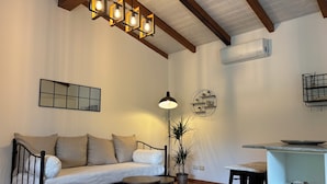 A living room with a sofa, a round table, a floor lamp, and a ceiling light fixture. - Luna & Limoni Country (Muravera)