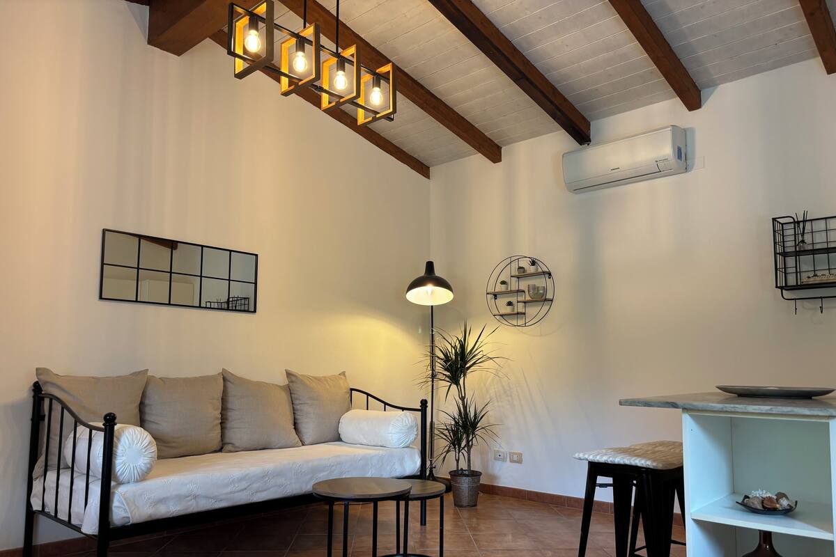Un salon comprenant un canapé, une table ronde, un lampadaire et un luminaire au plafond.