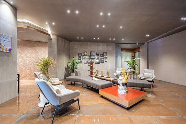 Um lobby moderno com área de estar, uma mesa de centro e uma parede decorada com quadros.